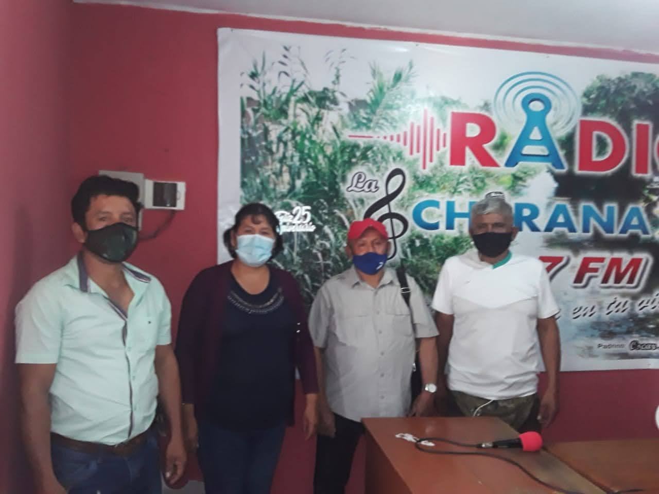 Four union leaders in masks stand in a local radio studio in front of the station banner