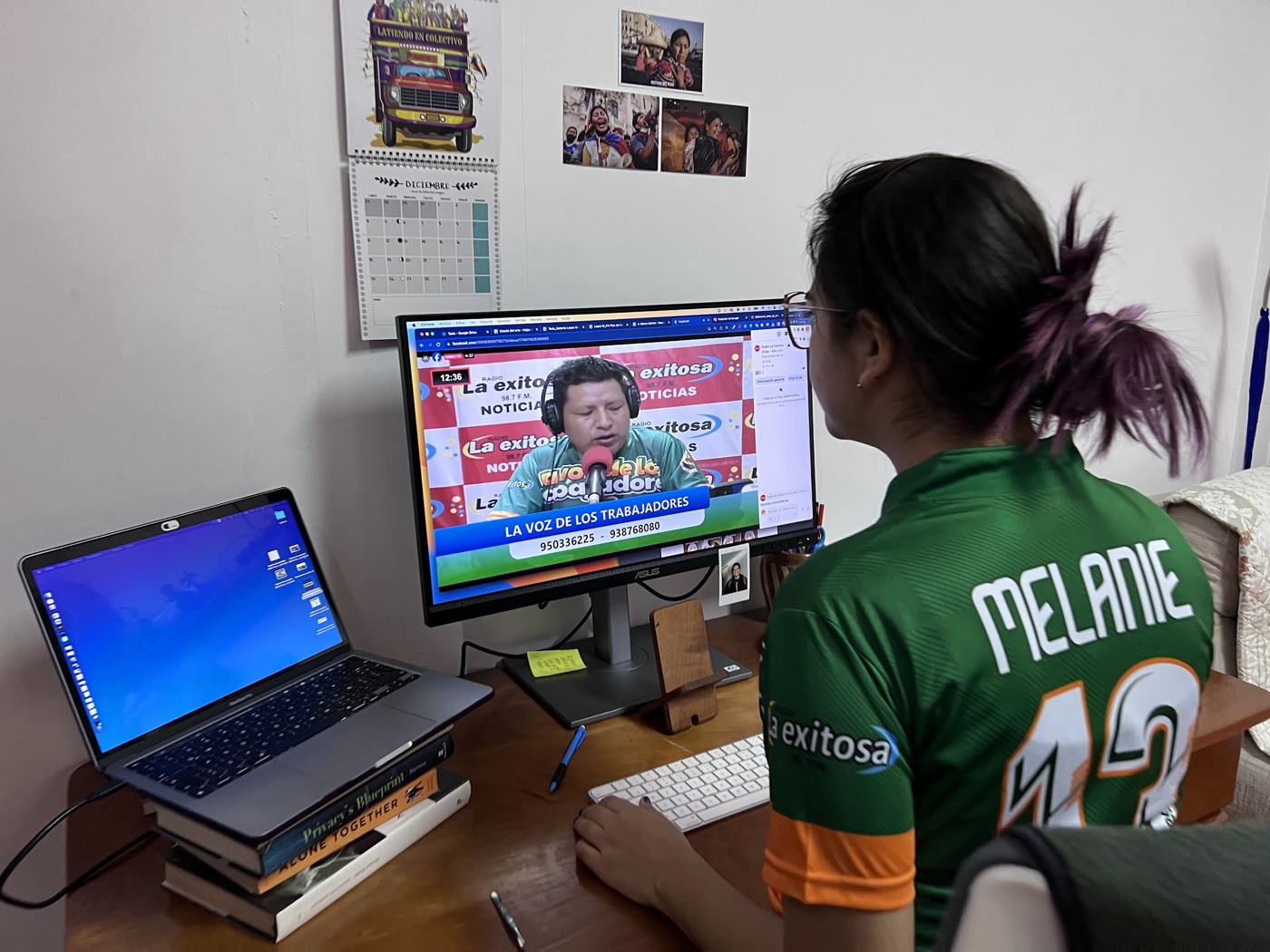 Melanie at her desk watching the live broadcast of La voz de los trabajadores