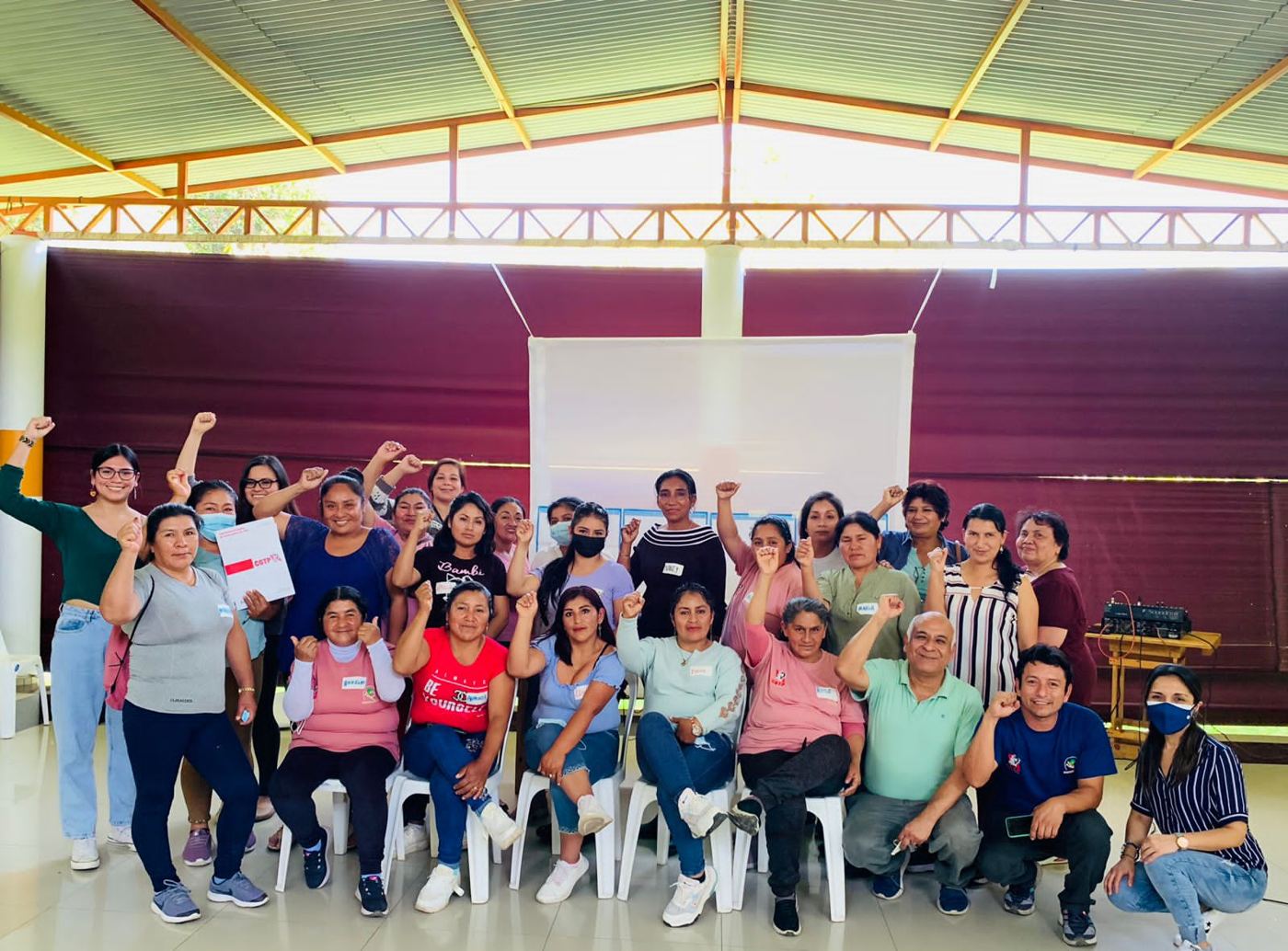 A group of women union leaders and facilitators pose with raised fists after a workshop